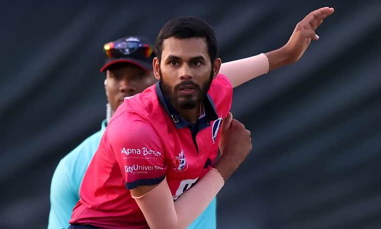 Cricketer in pink jersey preparing to bowl during a match.