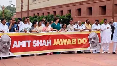 Protesters hold a banner with Prime Minister Narendra Modi's image and the message 'Amit Shah Jawab Do'.