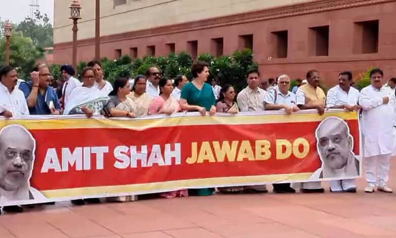 Protesters hold a banner with Prime Minister Narendra Modi's image and the message 'Amit Shah Jawab Do'.
