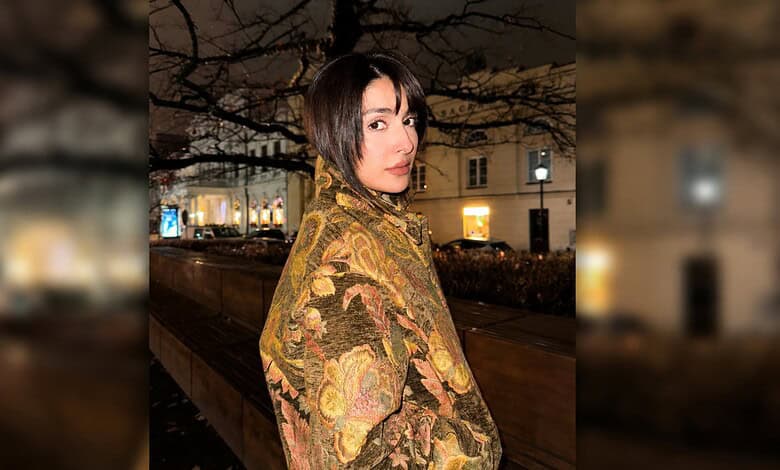 Ayeza Khan in a floral shawl, posing outdoors at night in a city setting.