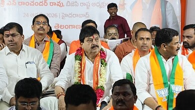 Telangana BJP leaders at a political event, wearing saffron and green scarves, seated on stage.