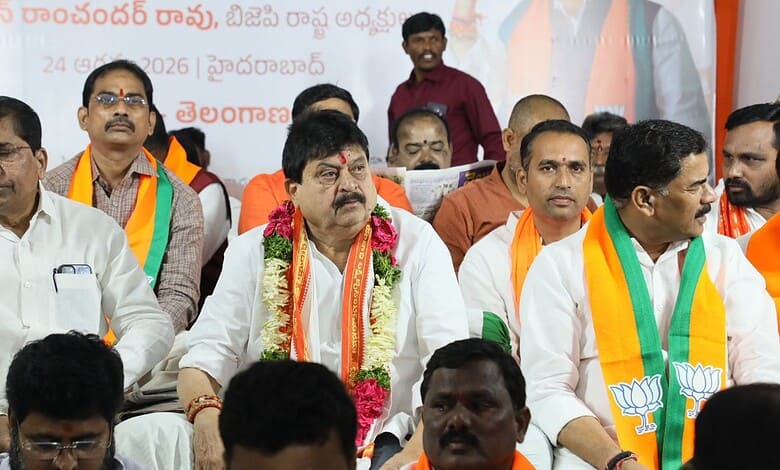 Telangana BJP leaders at a political event, wearing saffron and green scarves, seated on stage.