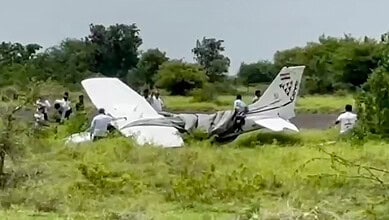 Local residents and officials gather around the wreckage of a trainer aircraft that crash-landed near the airstrip at Baramati Airport, in Pune district, Maharashtra, Sunday, Aug. 9, 2026.