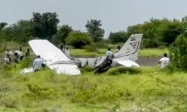 Local residents and officials gather around the wreckage of a trainer aircraft that crash-landed near the airstrip at Baramati Airport, in Pune district, Maharashtra, Sunday, Aug. 9, 2026.