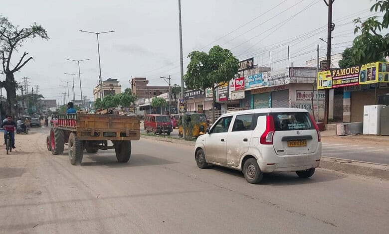 Poorly maintained Barkas-Pahadishareef road with potholes and low lighting, vehicles navigating unevenly.