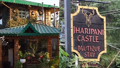 Haripani Castle Boutique Stay signboard outside a lush green area in India.