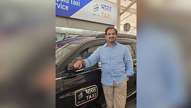 Man standing next to a Bharat Taxi vehicle at a transportation hub in Telangana.