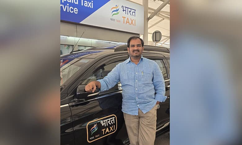 Man standing next to a Bharat Taxi vehicle at a transportation hub in Telangana.