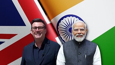 UK PM Burnham and Indian PM Modi at a diplomatic event with flags in the background.