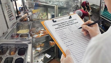 Food safety inspector inspecting food items at a restaurant kitchen with a clipboard.