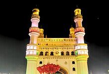 Illuminated historic mosque with tall minarets at night, vibrant lighting and clear sky.