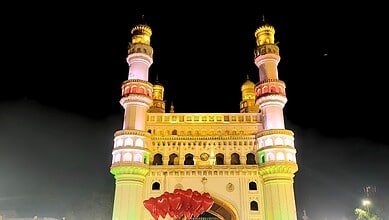 Illuminated historic mosque with tall minarets at night, vibrant lighting and clear sky.