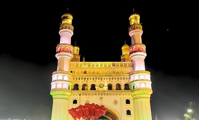 Illuminated historic mosque with tall minarets at night, vibrant lighting and clear sky.