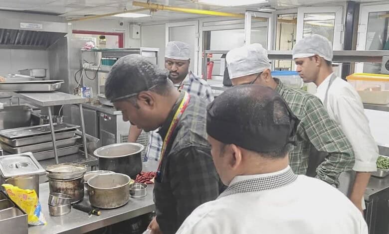 Kitchen staff inspecting food safety standards at a Bengaluru restaurant during an official check.