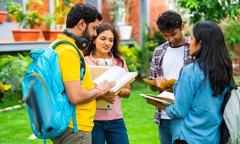 Group of diverse students studying outdoors in a lush green campus setting.