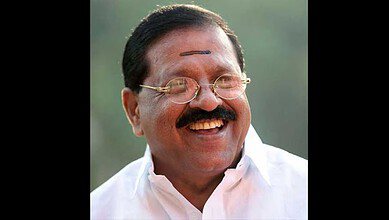 Indian politician Unnithan smiling, wearing glasses and traditional attire.