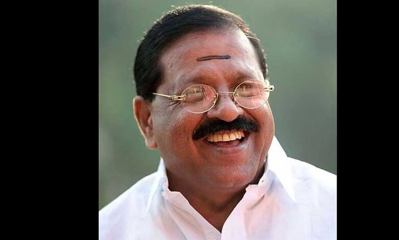 Indian politician Unnithan smiling, wearing glasses and traditional attire.