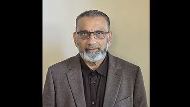 Hajji Mohammed Fazal, new president of FIANZ, wearing glasses and a suit, looking at the camera.