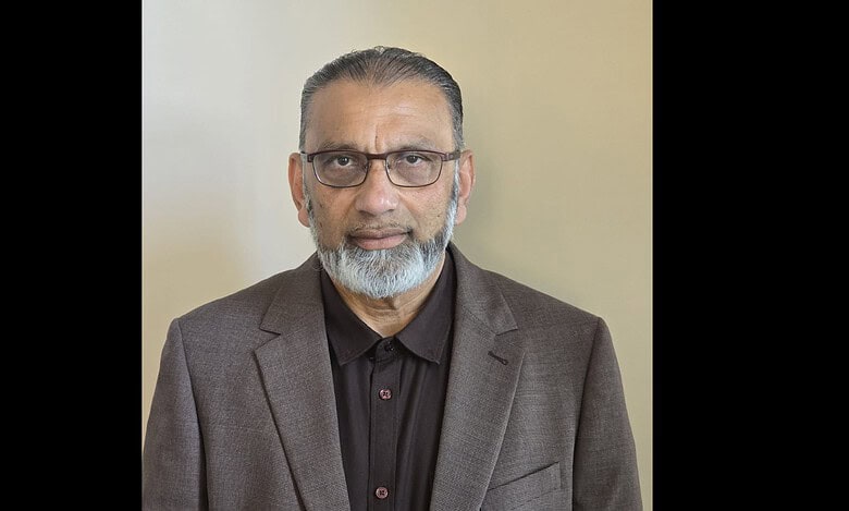 Hajji Mohammed Fazal, new president of FIANZ, wearing glasses and a suit, looking at the camera.