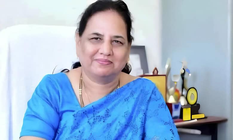 Waheeda Sultana in a blue saree smiling at her desk in an office setting.