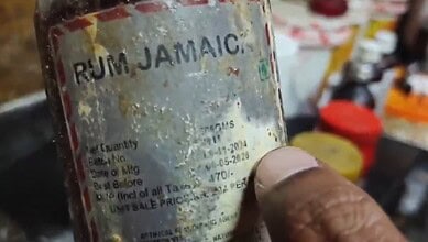 Close-up of a weathered rum Jamaica bottle with faded label and visible wear.