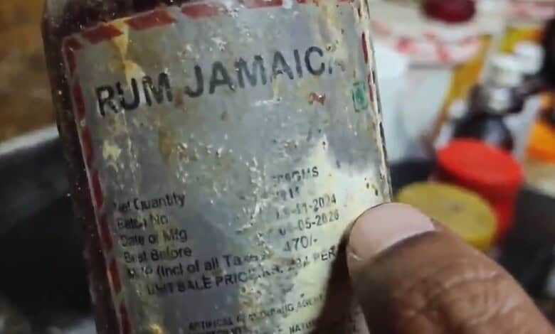 Close-up of a weathered rum Jamaica bottle with faded label and visible wear.