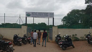 Group of young men standing outside a gated sports facility in Hyderabad, India.