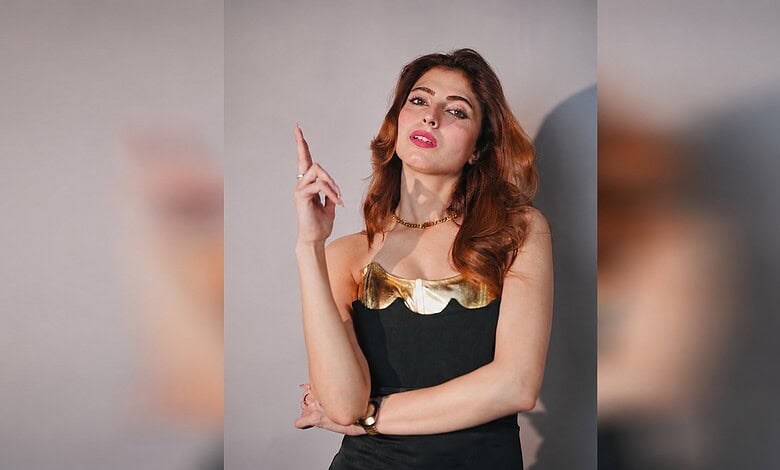 Farrhana Bhatt posing with a confident expression, pointing upwards, in a stylish black and gold outfit.