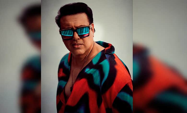 Govinda wearing a vibrant jacket and sunglasses, posing for a photo in a casual setting.