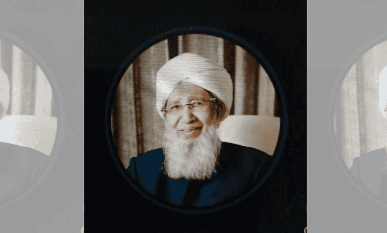 Grand Mufti with white beard and turban, smiling, seen through a circular mirror.
