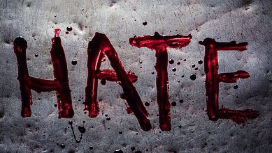 The word 'HATE' written in red blood-like substance on a grey surface.