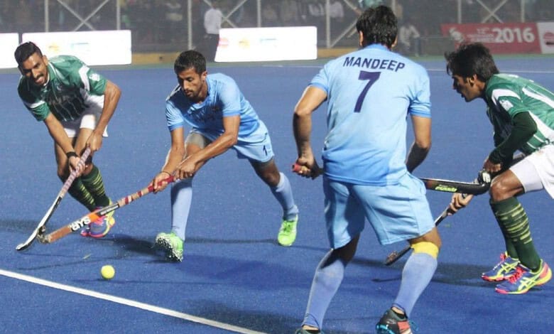 India and Pakistan field hockey players compete fiercely during a match.