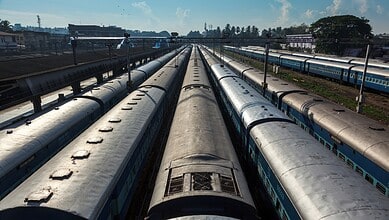 Multiple train tracks with trains at a railway station, under a clear blue sky.