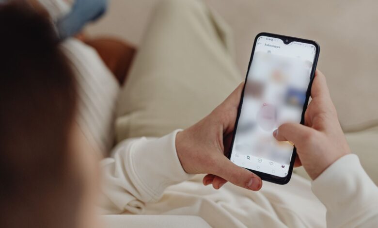 Person using a smartphone while sitting on a sofa, browsing content.