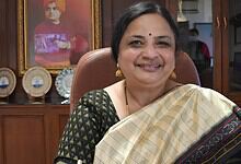 JNU Vice-Chancellor smiling in office, wearing traditional saree and gold jewellery.