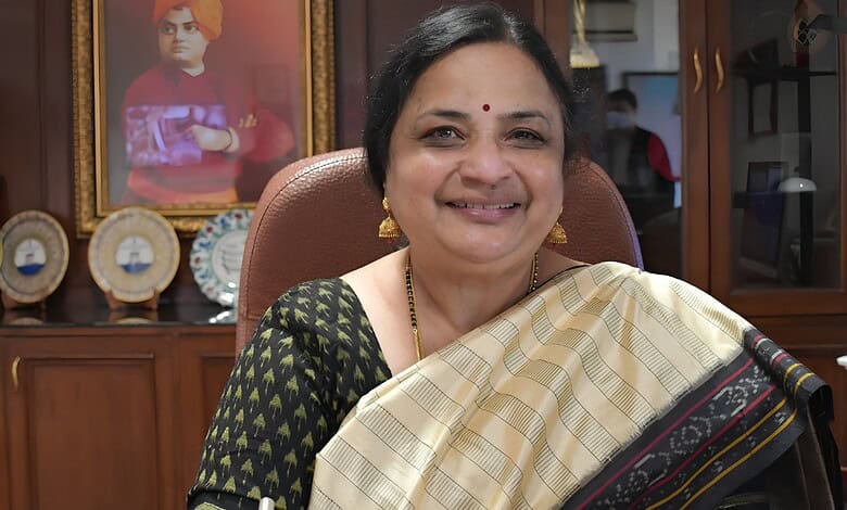 JNU Vice-Chancellor smiling in office, wearing traditional saree and gold jewellery.