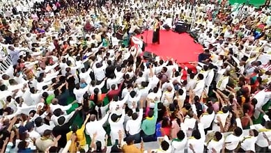Large crowd gathered at a political rally with a stage and red carpet in the centre.