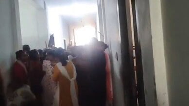 Students involved in a clash over stolen phones at Andhra college, with a crowd gathered in a corridor.