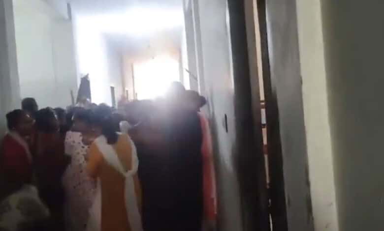 Students involved in a clash over stolen phones at Andhra college, with a crowd gathered in a corridor.