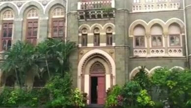 Exterior view of a historic Mumbai library with lush greenery and ornate architecture.