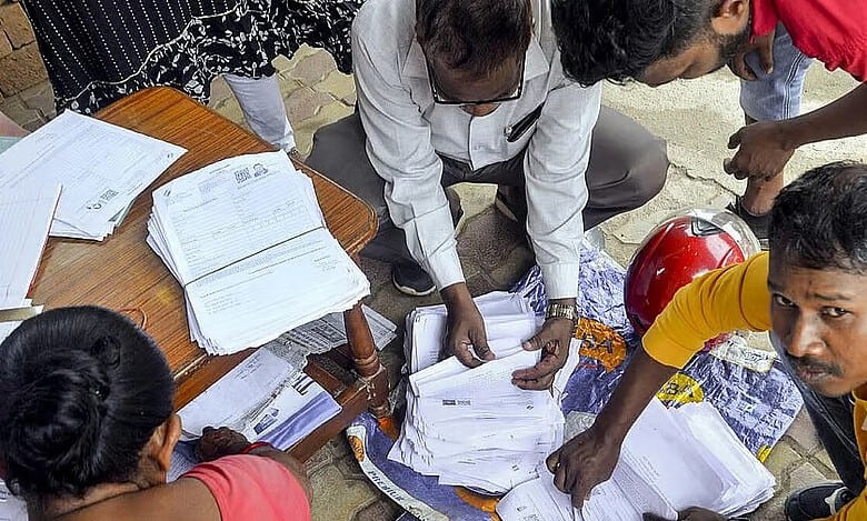 Voters' list verification process with officials and volunteers handling documents outdoors.