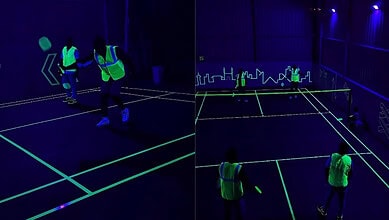 People playing badminton on a neon-lit dark court in Hyderabad.