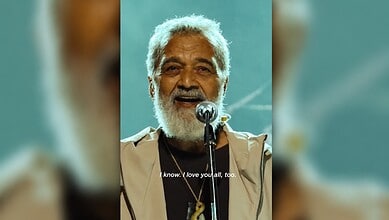 Lucky Ali singing on stage with a microphone, smiling, with a heartfelt expression.