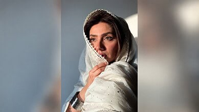Mahira Khan wearing a white traditional dress with a headscarf, looking contemplative.