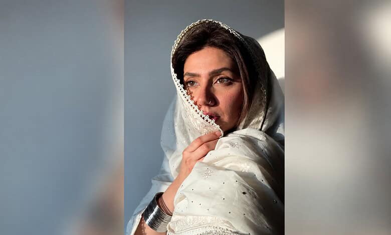 Mahira Khan wearing a white traditional dress with a headscarf, looking contemplative.