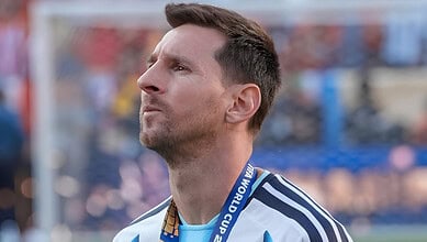Lionel Messi wearing a World Cup medal and a blue and white jersey, celebrating his victory.