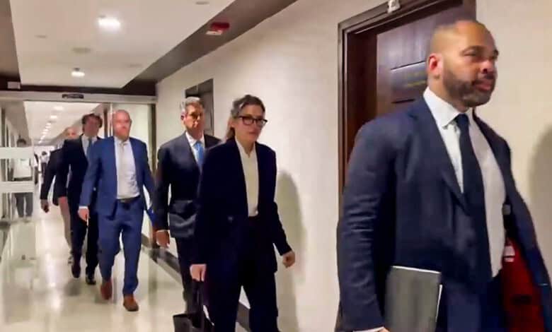 Group of professionals walking in a corridor, dressed in formal business attire.