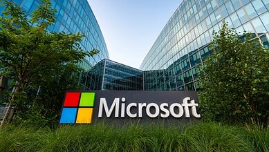 Microsoft logo outside a modern office building in Hyderabad, India, with greenery around.