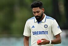 Indian cricketer in white jersey holding a pink cricket ball on the field.