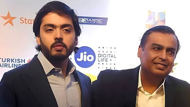 Two men in formal attire at a Jio event with logos in the background.